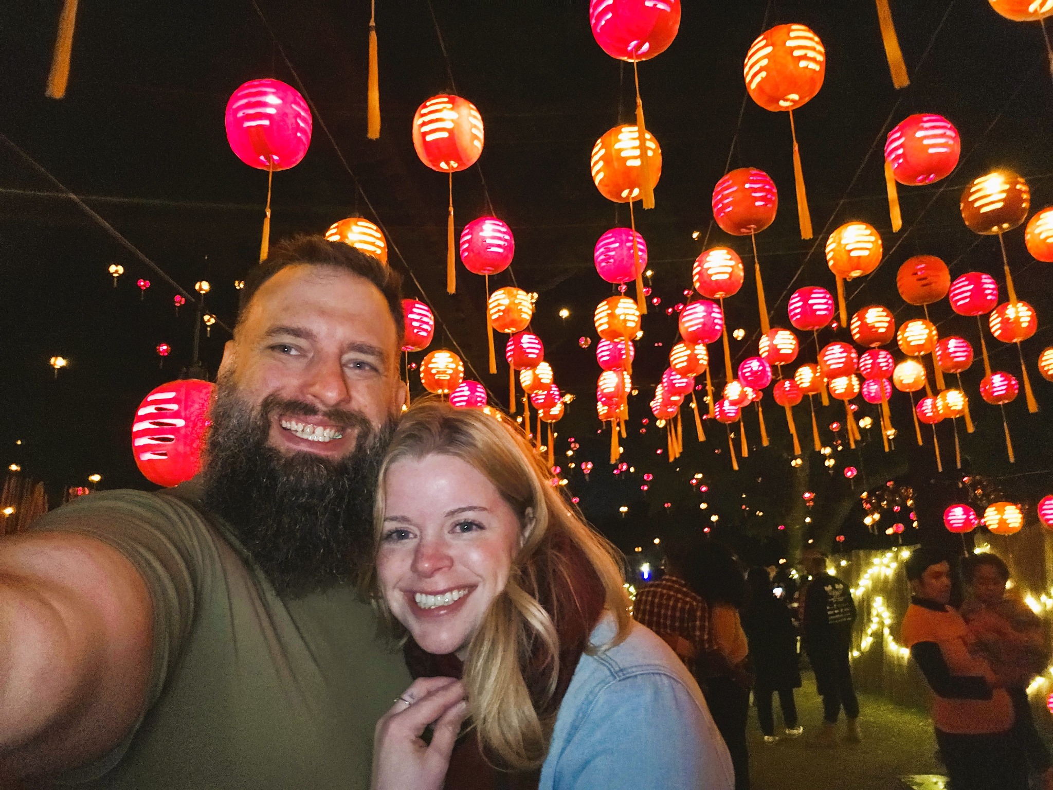 McKenzi and Justin smiling together beneath glowing lanterns